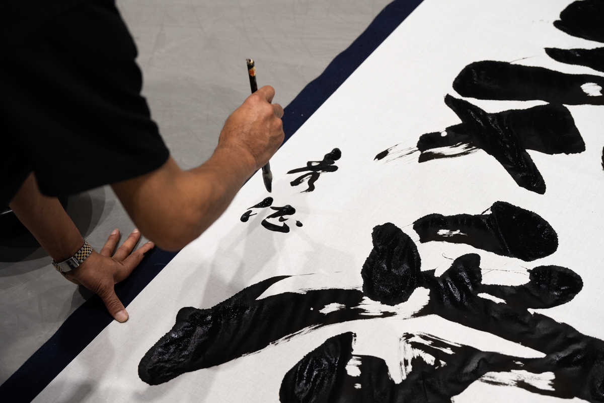 書き上げた作品にサインを書き込む中山秀征さん